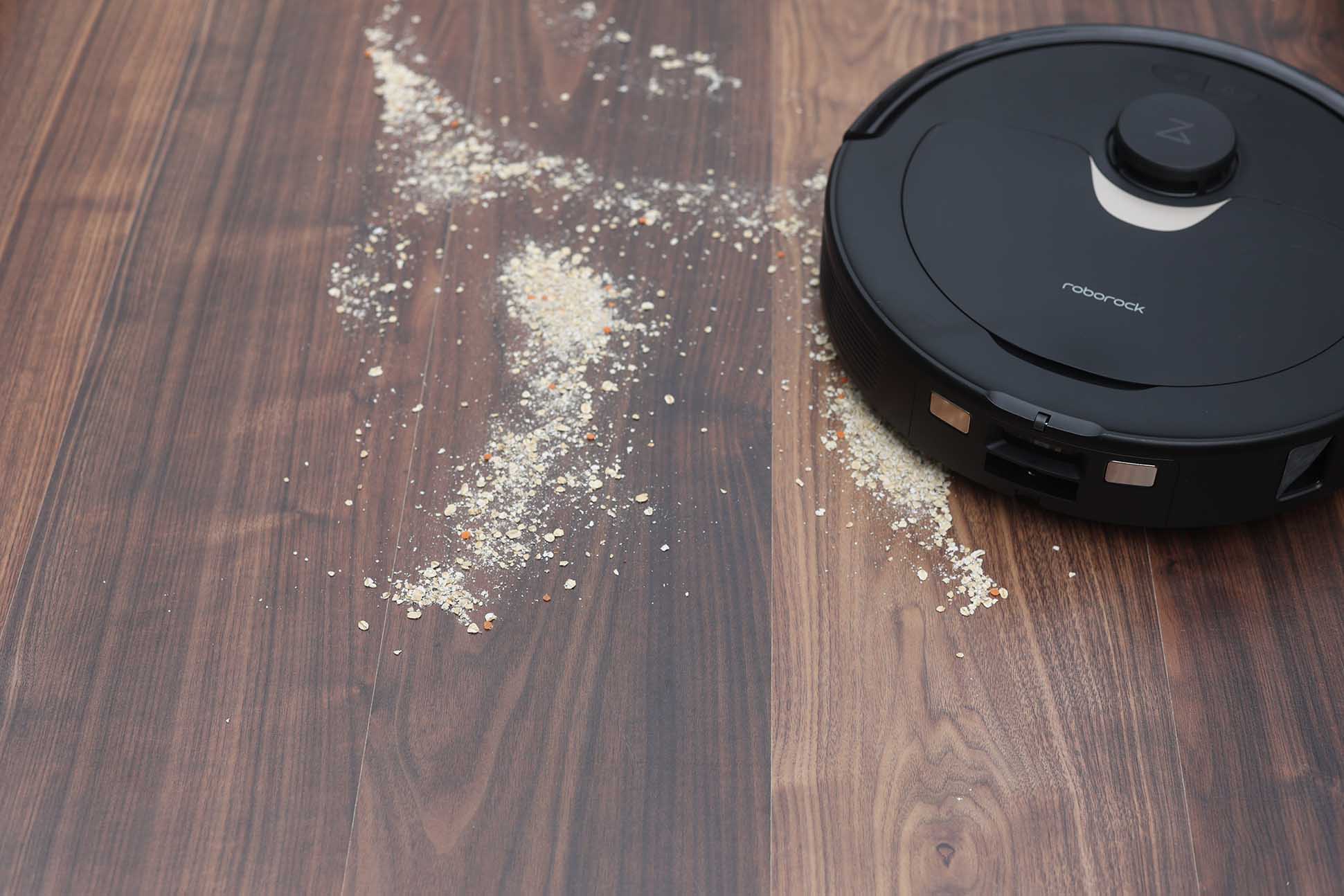 Der Roborock Q Revo reinigt Haferflocken beim Saugtest auf dem Laminat.